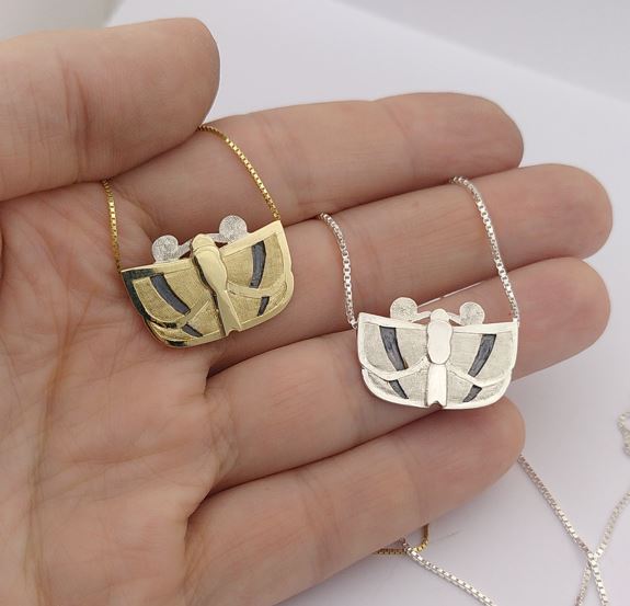Two pendants with a butterfly form, one in silver one in gold. Made by hand by Casez Jewellery.