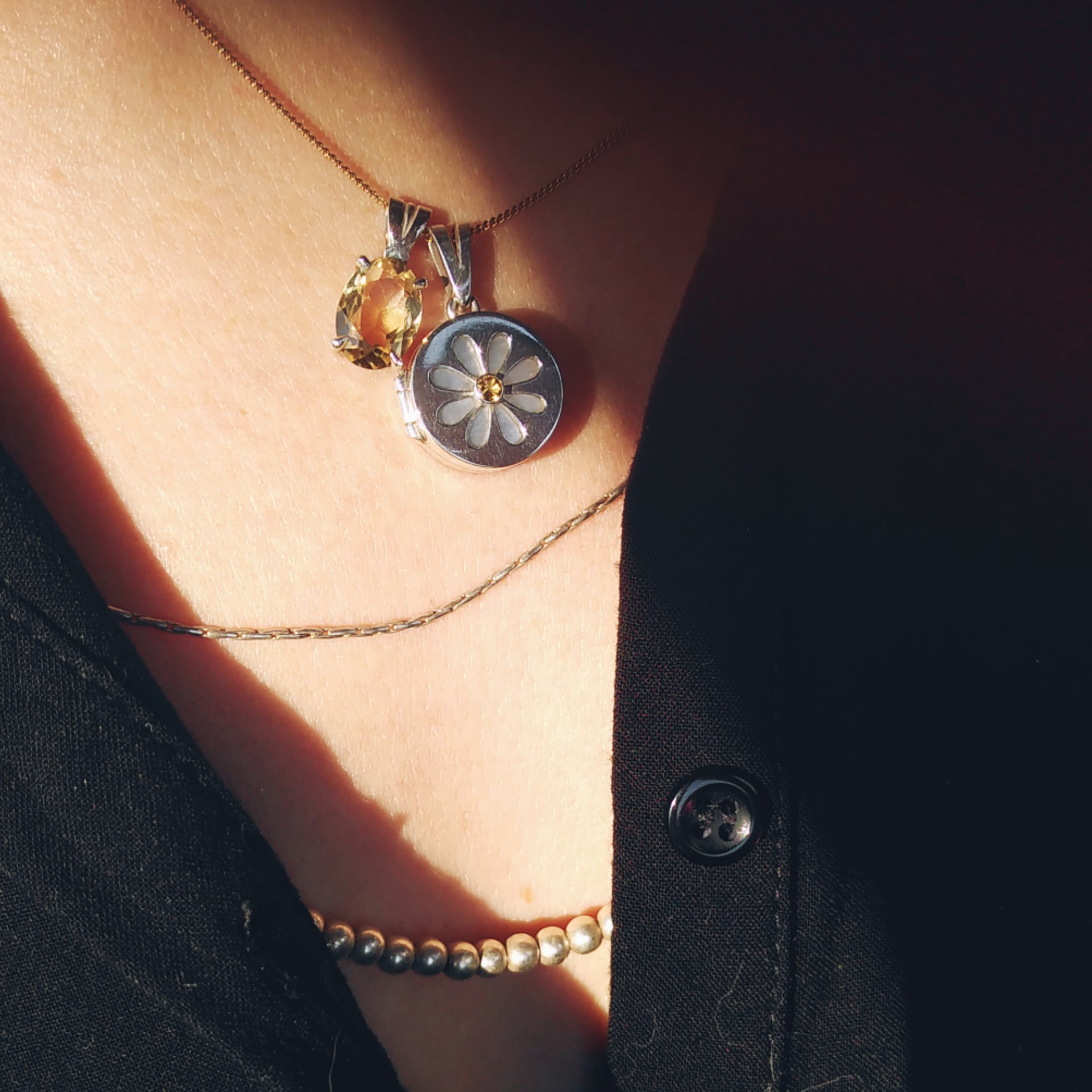 The daisy pendant displayed on a person, with two silver chains and a citrin pendant in oval cut. Made by hand by Casez Jewellery.
