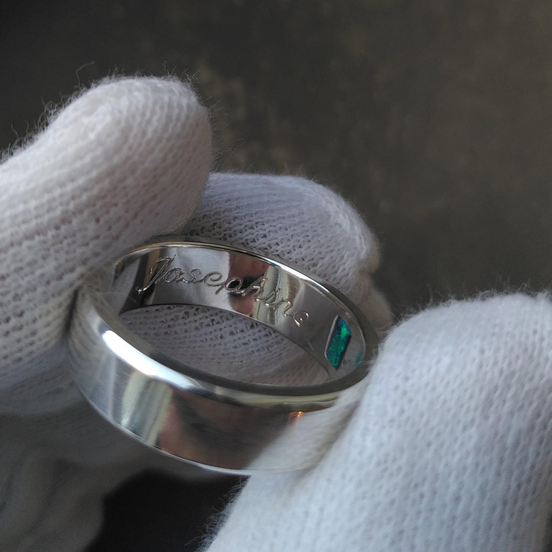 A thick sterling silver ring in which the name Josephine is engrave. Inside the ring, a small squared opal in strong green blue colors is set. Made by hand by CASEZ Jewellery.