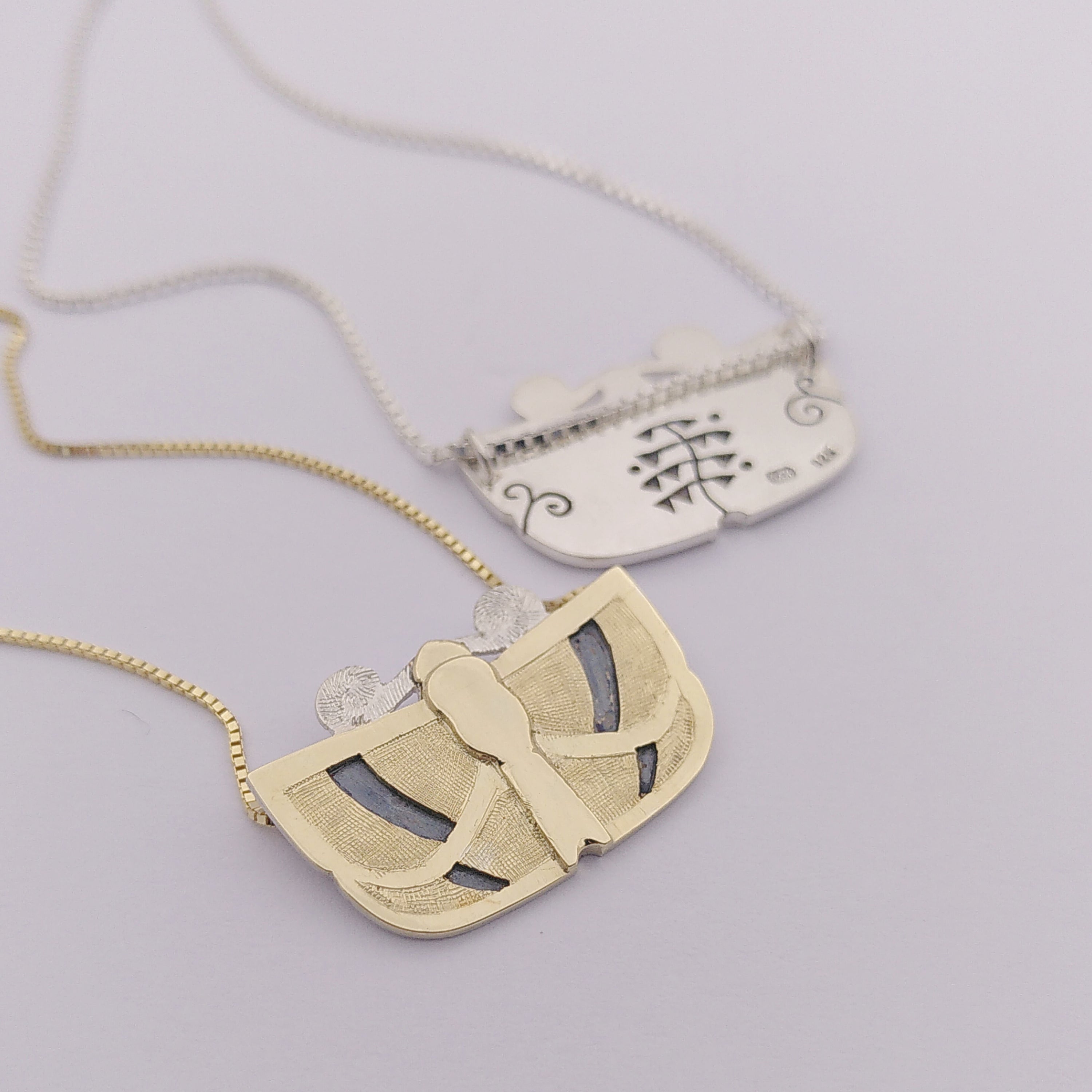 Two pendants in a butterfly shape, one in silver one in gold. Made by hand by Casez Jewellery.